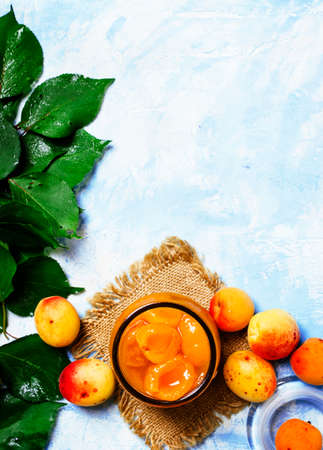 Apricot jam with fresh apricots with leaves, top viewの写真素材