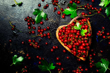 Red currants in a wooden bowl, black background, top viewの写真素材