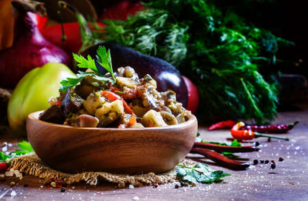 Saute from aubergines in bowl, dark wooden background, low key, selective focus