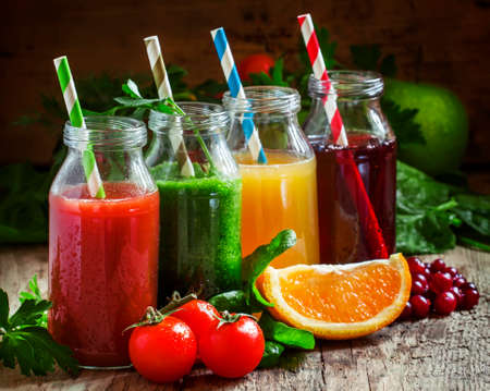Bottles with fresh juices from fruits and vegetables on an old wooden background, selective focusの写真素材