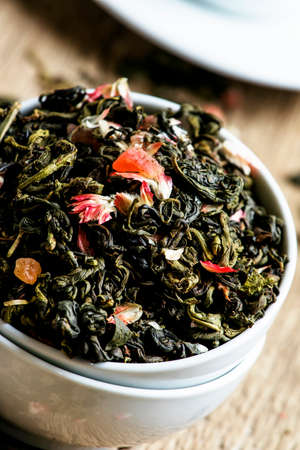 Ceylon green tea with petals of cherry blossom and dried fruits, vintage wooden background,...