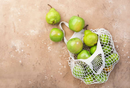 Fruits in reusable eco-friendly string mesh bag. Zero waste, plastic free and sustainable lifestyle concept. Brown kitchen table background, copy space, top viewの写真素材