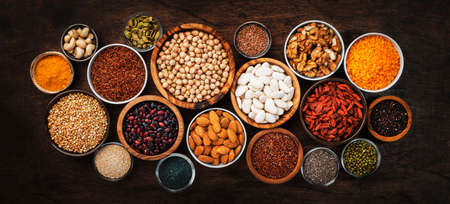 Superfoods, legumes, nuts, seeds and cereals set in bowls on wooden background. Superfood as chia, spirulina, beans, goji berries, quinoa, turmeric, mung bean, buckwheat, lentils, flax seed, wild rice and almond. Copy space, top viewの写真素材