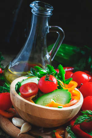 Fresh spring salad with bell pepper, tomato, cucumber, herbs and spices with olive oil, selective focusの写真素材