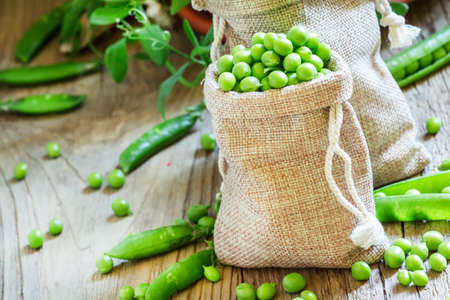 Peeled green peas in canvas bags, vintage wooden background, selective focusの写真素材