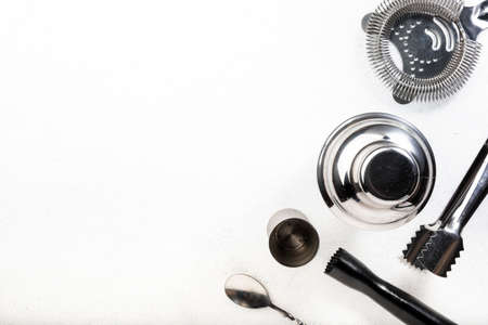 Steel bar tools and accessories for making cocktail. Shaker, jigger, strainer, spoon, tongs, muddler. Alcohol drink and beverages preparation concept. White background, top view, copy spaceの写真素材