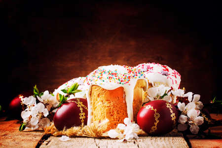 Easter cake and red painted eggs, white apricot flowers, festive composition in rustic style,...