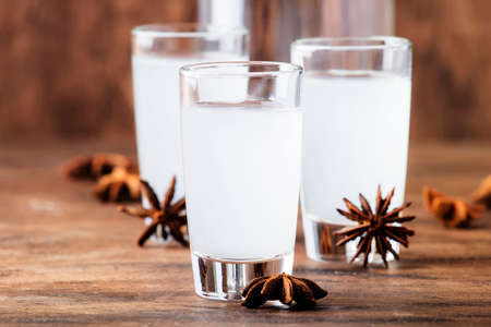Ouzo - Greek anise brandy, traditional strong alcoholic drink in glasses on the old wooden table,...