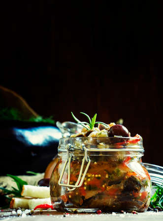 Homemade Eggplant Caponata with black olives in a glass jar, vintage wooden background, selective focusの写真素材