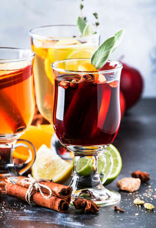 Mulled wine and mulled cider. Hot winter drinks and cocktails in glass mugs with spices and citrus fruitの写真素材