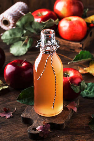 Apple vinegar. Bottle of apple organic vinegar made from fermented apples on wooden background. Healthy organic food.の写真素材