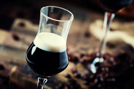 Two-layer cocktail with coffee liqueur, vintage wood background, selective focus