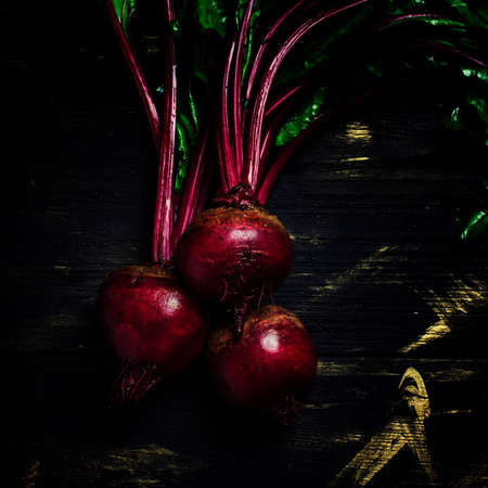Fresh beet with tops, dark background, low key, top view