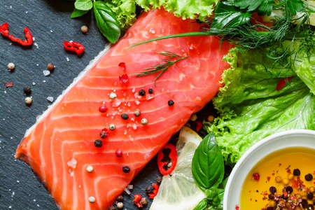 Tasty piece of salmon fillet with herbs, spices, lemon, salt, pepper, top view, selective focusの写真素材