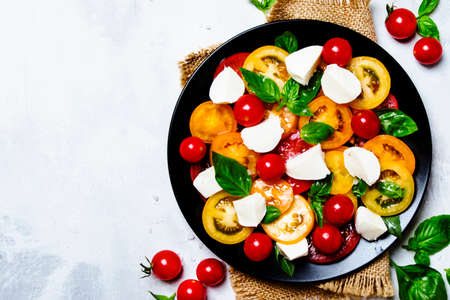Spring salad with tomato, cheese and basil, gray background, top viewwの写真素材