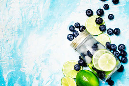 Summer cold drink with blueberry, lime and ice in glass bottle, top viewの写真素材