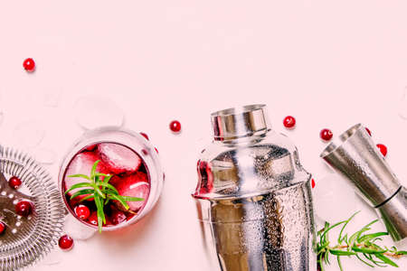 Cranberry cocktail with ice, rosemary and berries, bar tools, white background, top viewの写真素材