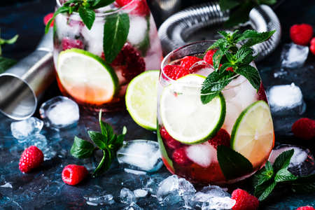 Summer cool alcoholic cocktail raspberry mojito cocktail with lime, rum, mint and ice. Bar tools, gray background, selective focusの写真素材