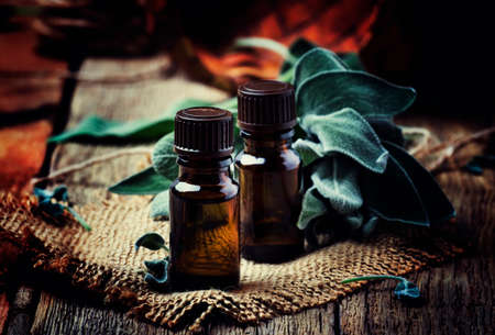 Essential sage oil in brown bottle on the vintage wooden blackground, rustic style, selective focusの写真素材