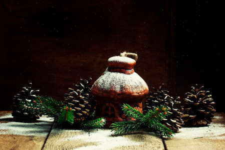 Christmas House from clay with pine cones and fir branches under the snow, vintage wooden background, selective focusの写真素材