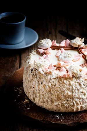 Meringue cake and a cup of coffee, vintage wooden background, selective focus