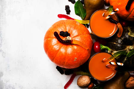 Halloween background with pumpkin juice, disgusting worms and black sweets, top viewの写真素材