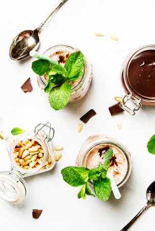 Chocolate milkshake or cocktail with green mint and cedar nuts, top view