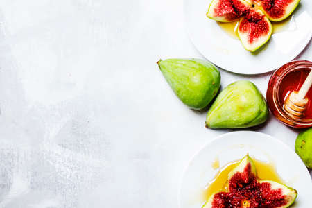 Sweet fresh green figs with honey, summer dessert, gray stone background, top view