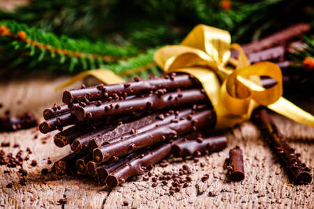 Christmas present chocolate on old wooden background with fir branches and pine cones, selective focusの写真素材