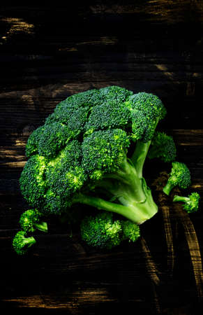 Fresh broccoli on a dark wooden background, low key, top viewの写真素材