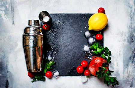 Bloody mary alcoholic cocktail with red tomato, lemon juice, hot sauce, green celery and russian vodka, black stone background, top viewの写真素材