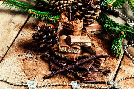 Different chocolate and cocoa powder, tree branches and pine cones, vintage wooden background, selective focusの写真素材
