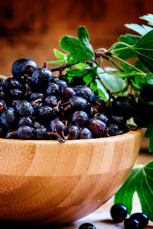 Black currant in bowl, vintage wooden background, selective focusの写真素材