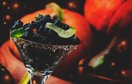 Halloween black candy cats in a glass and pumpkin guards, festive background, low key, selective focus and toned imageの写真素材