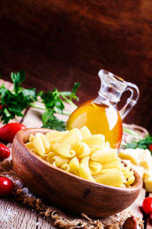 Castellane Dried pasta in a bowl, olive oil, tomatoes, garlic and cheese, vintage wooden background, selective focusの写真素材