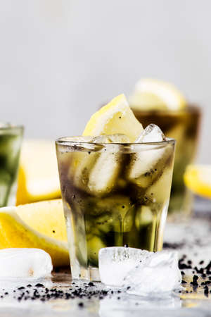 Healthy food and drink concept: iced black detox lemonade water with crushed ice and lemon slices in...