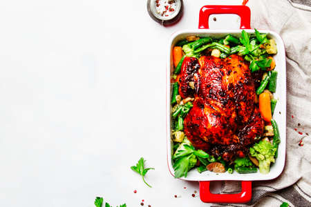 Baked chicken in honey glaze with garnish of vegetables, white background, top viewの写真素材