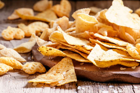 Mexican corn chips, nachos with salt, vintage wooden background, selective focus