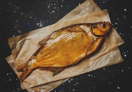 Golden smoked river bream on dark background, top view