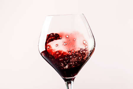 Dry red wine, splash in glass, pink background, defocused in motion image, shallow depth of fieldの写真素材