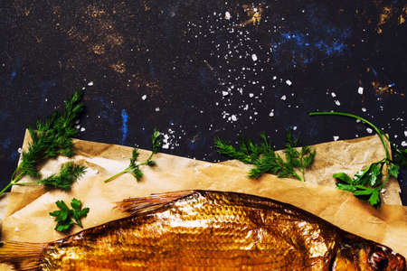Smoked river bream on dark background, top view