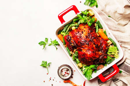 Baked chicken in honey glaze with garnish of vegetables, white background, top viewの写真素材