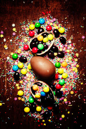 Easter background with chocolate eggs and multi-colored sugar, top view