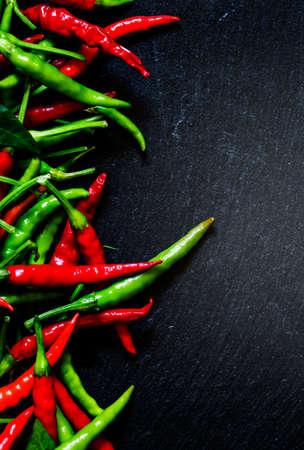 Spicy peppers on a dark background, top view