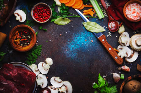 Food cooking background. Fresh organic vegetables, ingredients, spices and meat for warm autumn soup on vintage kitchen table with rustic wooden cutting board. Top view, place for text. Domestic cooking and eating conceptの写真素材