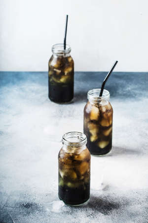 Healthy food and drink concept: cold black detox mineral water with crushed ice in glass bottles,...