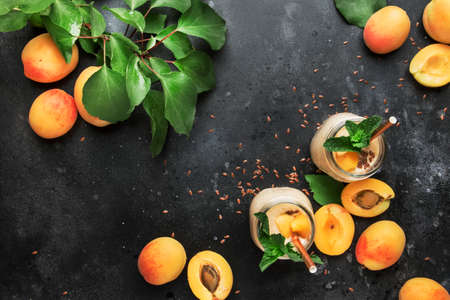 Healthy apricot smoothies in glass bottles and fresh fruits, top view