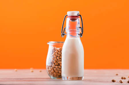 Soy milk and soy bean on orange background. Non-dairy milk concept. Vegan Drink. Copy spaceの写真素材