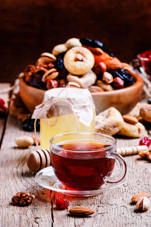 Middle East black tea in a cup with dried fruits and nuts. Vintage wooden background, selective focusの写真素材