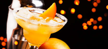 Mango daiquiri, alcoholic cocktail with white rum, liqueur, syrup, lemon juice, mango and ice on black bar counter background, copy space, selective focusの写真素材